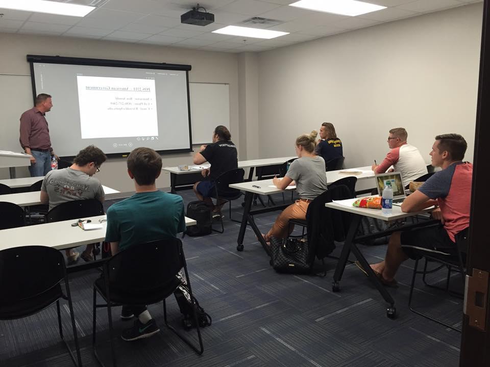 A Howard Payne University classroom setting with students looking towards a teacher and a projected presentation. | HPU